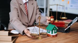 Real Estate Lawyer and Foreclosure Law: House model with a judge's gavel on a table, representing foreclosure and bankruptcy concepts. White background.