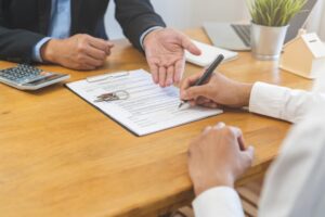 Asian tenant signing a rental or purchase contract with a landlord, realtor, and banker, completing a mortgage agreement or loan.