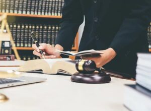 Lawyer reviewing legal documents and reference books with a gavel in the foreground, symbolizing the work of a pardons attorney.