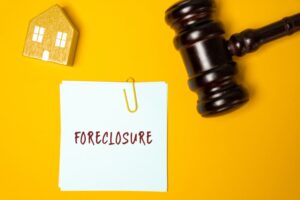 Legal process in which the ownership shifts to the bank or lender if the homeowner fails to pay the loan. Notes, house and judge's gavel