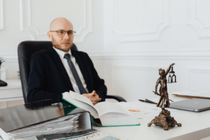 bald man sitting wearing eyeglasses and black suit