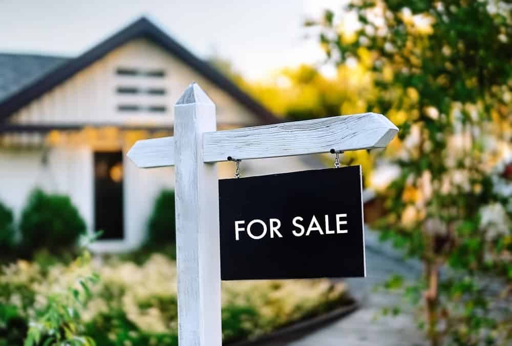 Close-up of for sale sign in font of house.