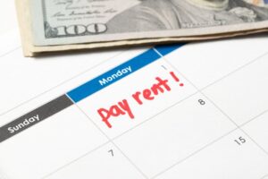 Calendar with the words pay rent written in red ink and with US dollar bills.