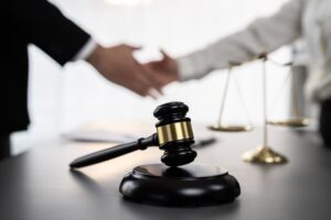 Focus gavel symbolize justice on blur background of lawyer colleagues handshake after successful legal deal for lawsuit to advocate resolves dispute in court